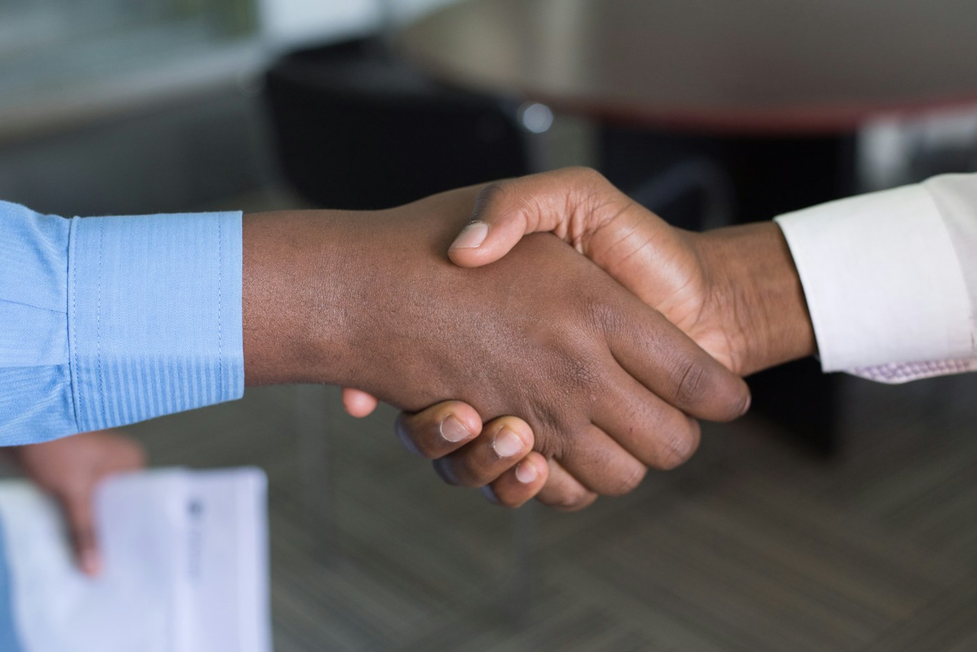 Two business professionals shaking hands across a meeting table